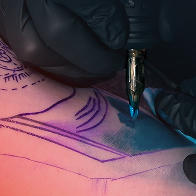 Eine Nahaufnahme einer Person, die eine blaue Schattierung in ihrem Tattoo erhält.